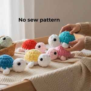 Puede incluir: Una colección de tortugas de ganchillo de colores, incluyendo azul, rojo, amarillo y rosa. El texto "No sew pattern" es visible. Las tortugas tienen cabezas blancas y ojos negros pequeños. Algunas están dispuestas en una pequeña cesta.