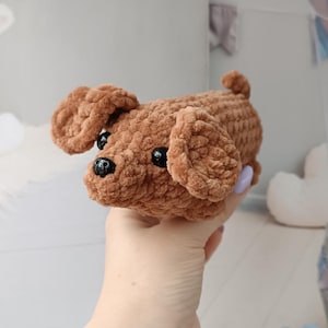 May include: A handmade brown crochet dog with floppy ears, a small tail, and black bead eyes. The plush toy is made of soft, textured yarn. A cute, cuddly stuffed animal.