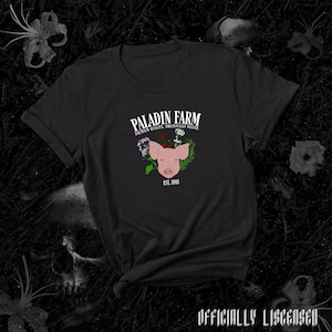 May include: Black t-shirt with a white graphic of a pig with flowers around its head. The text "PALADIN FARM" is above the pig and "PREMIUM QUALITY, ORGANICALLY RAISED" is below the pig. The text "EST. 2018" is below the pig's head.