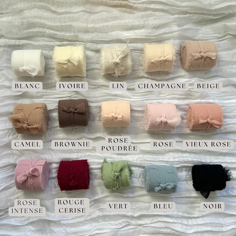 Puede incluir: Una colecci&oacute;n de 15 rollos de cinta de tela en varios colores, incluyendo blanco, marfil, beige, camel, marr&oacute;n, rosa, rojo, verde, azul y negro. Cada rollo est&aacute; atado con un lazo y etiquetado con el nombre del color en franc&eacute;s.