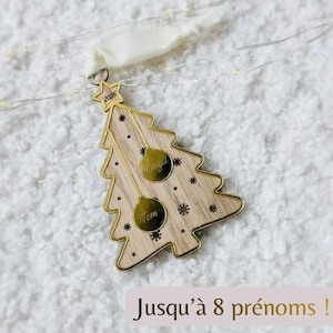 Könnte beinhalten: Weihnachtsbaumschmuck aus Holz mit goldenem Rand, Sternaufsatz und zwei goldenen Kugeln. Der Schmuck hat die Namen "Meryl" und "Tom" auf den Kugeln eingraviert. Das Jahr "2025" ist auf dem Stern eingraviert. Der Text "Jusqu'à 8 prénoms !" steht unten.