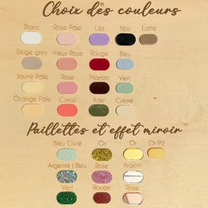 K&ouml;nnte beinhalten: Eine Farbkarte auf einer hellen Holzoberfl&auml;che mit Reihen ovaler Farbmuster. Der Text lautet Choix des couleurs und Paillettes et effet miroir. Die Muster zeigen verschiedene Volltonfarben, Glitzer-Finishes und spiegelnde Metallic-Effekte.