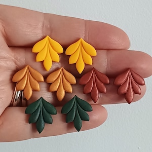 Puede incluir: Seis pares de pendientes en forma de hoja en varios colores otoñales, incluyendo amarillo, naranja, marrón y verde.