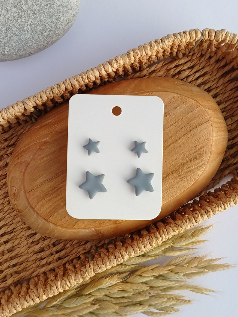 2 pairs of grey star shaped stud earrings in on a white display card
