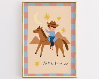 Puede incluir: Ilustración enmarcada de un vaquero de dibujos animados montado en un caballo marrón. El vaquero lleva un sombrero marrón y una camisa azul. El fondo es beige con una luna creciente, estrellas y la palabra "yeehaw". El marco tiene un borde dorado.