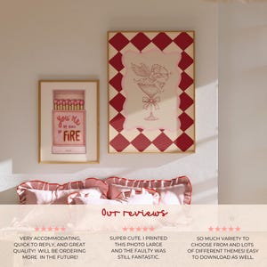 May include: Two framed art prints. One features a matchbox with the text "you're my kind of fire." The other has a cupid in a cocktail glass with a red and cream diamond pattern border. The prints are displayed above a bed.