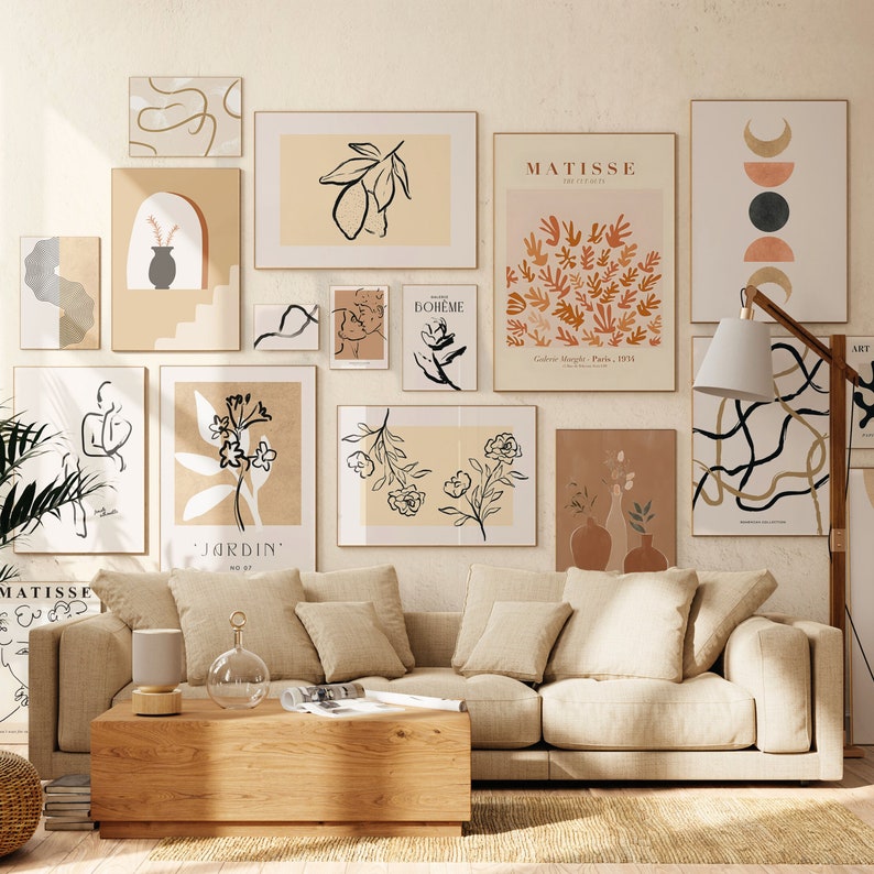 May include: A living room interior design with a beige sofa and a coffee table. The walls are decorated with a collection of abstract art prints in black, white, and brown. The prints feature various designs, including leaves, flowers, and geometric shapes. The text on the prints includes "Jardin", "Boheme", and "Matisse".