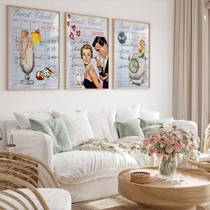 May include: Three vintage-style prints with a blue and white check background. Each print features a cocktail glass with a different drink and a woman in a retro outfit. The first print features a woman in a white swimsuit holding a pineapple. The second print features a woman in a red dress with a man in a suit. The third print features a woman in a green dress holding a lime.
