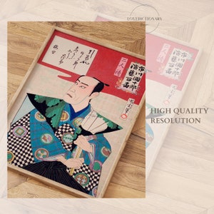 May include: A framed Japanese woodblock print depicting a man in a blue and black patterned robe holding a fan. The print is titled "市川團十郎 演藝百毒" in Japanese characters.