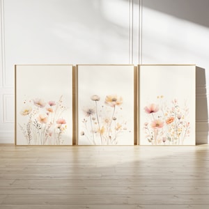 Può includere: Set di tre stampe ad acquerello incorniciate con delicate illustrazioni floreali in tonalità rosa, beige e giallo. Le stampe raffigurano un campo di fiori selvatici con un'estetica morbida e romantica.