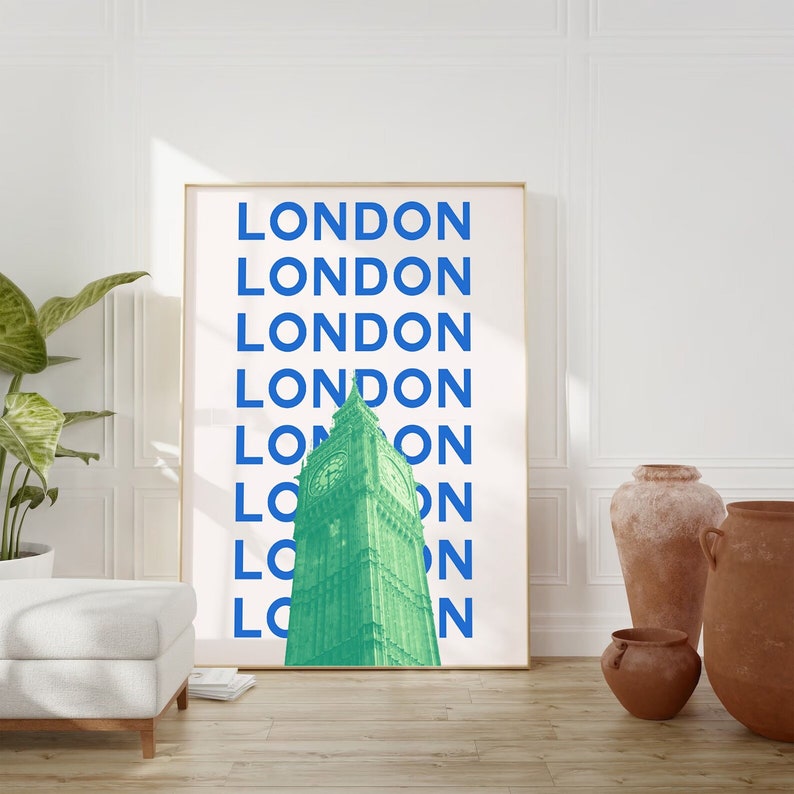 May include: A framed print with a white background and blue text that reads "LONDON" repeated multiple times. The text is stacked vertically. A green image of Big Ben is centered in the print.