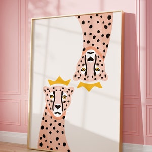 May include: A framed illustration of two pink cheetahs with black spots. The cheetah on the top is upside down and both cheetahs are wearing gold crowns.