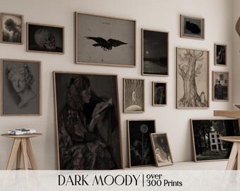May include: A collection of framed art prints in black frames, featuring a variety of subjects, including a skull, a raven, a tree, a woman reading, and a floral design. The prints are arranged on a white wall, with a wooden table and a stool in the foreground. The text "DARK MOODY | over 300 Prints" is visible at the bottom of the image.