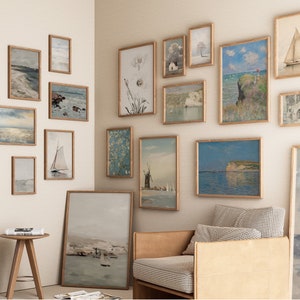 Puede incluir: Una pared de galer&iacute;a con una variedad de obras de arte enmarcadas, incluyendo paisajes marinos, paisajes y dise&ntilde;os abstractos. La pared est&aacute; pintada de un color beige claro y los marcos son todos de un color madera claro.
