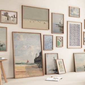 Puede incluir: Una pared de galer&iacute;a con una variedad de obras de arte enmarcadas, incluyendo paisajes, marinas y dise&ntilde;os abstractos. La pared est&aacute; pintada de un color beige claro y los marcos son todos de madera.