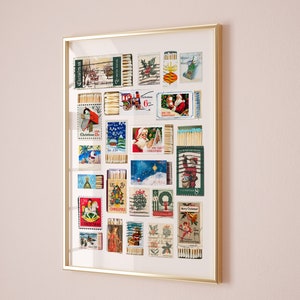 May include: A framed collage of vintage Christmas stamps, each featuring a different holiday design, including Santa Claus, a Christmas tree, and a train. The stamps are arranged in a grid pattern and are surrounded by a gold frame.