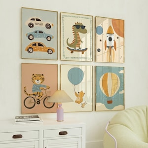 May include: Six framed art prints with cartoon illustrations. The prints feature cars, a dinosaur on a skateboard, a rocket, a tiger on a bicycle, a bear with a balloon, and a hot air balloon. The frames have gold-coloured edges.