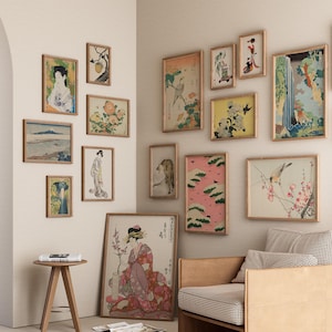 May include: A white wall with a collection of framed artwork featuring Japanese-inspired prints and paintings. The artwork includes images of birds, flowers, landscapes, and people. The frames are all made of wood and have a natural finish.