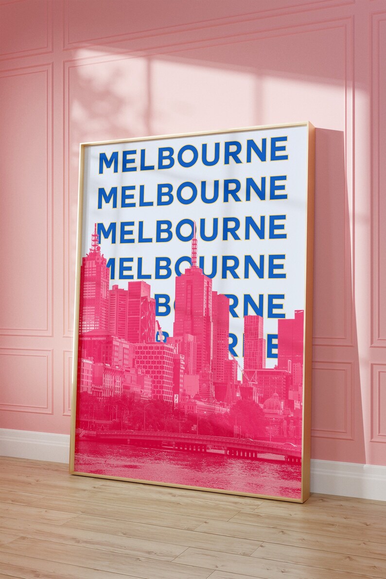 May include: A gold framed print with a white background and the word "MELBOURNE" repeated in blue and yellow lettering. The background image is a pink silhouette of the Melbourne skyline.