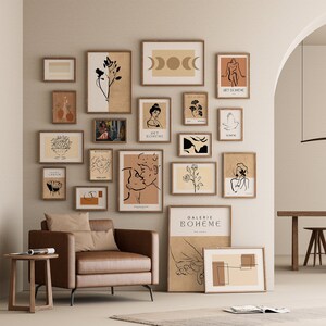 May include: A gallery wall with a variety of framed prints in black and white and brown tones. The prints feature abstract designs, line art, and minimalist illustrations. The prints are arranged in a grid pattern on a light beige wall.