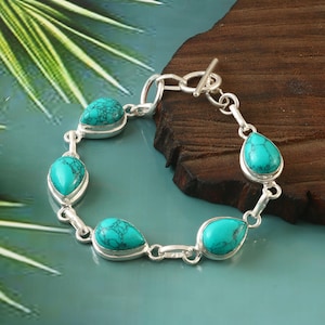 May include: A silver bracelet with five turquoise teardrop-shaped stones. The bracelet has a toggle clasp.