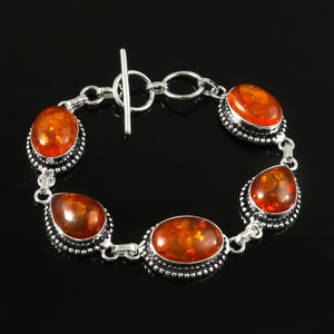 May include: A silver bracelet with four amber stones. The bracelet has a toggle clasp.