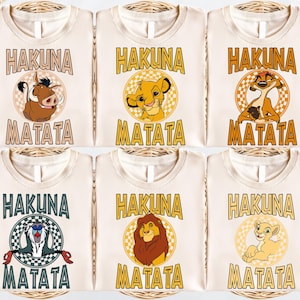 six white t-shirts with the text "HAKUNA MATATA" printed on them, featuring illustrations of the main characters from the Disney film "The Lion King".