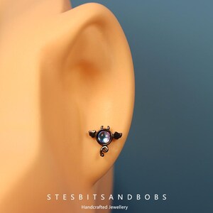 Peut inclure: Bijou de piercing de nez en forme de chauve-souris noire avec un gemme iridescent violet.