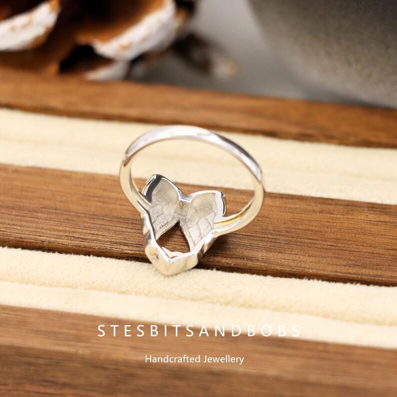 May include: A close-up of a silver ring with a butterfly-wing design. The ring is set on a wooden surface. The text "STESBITSANDBOBS" and "Handcrafted Jewellery" are visible at the bottom of the image.