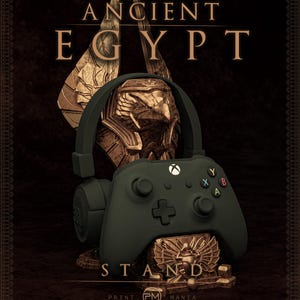 May include: A dark green Xbox controller stand with an Ancient Egypt theme. The stand features a gold-coloured bust and wings, with the words "ANCIENT EGYPT STAND". The Print Mania Studios logo is at the bottom.