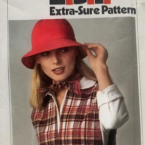 May include: A Simplicity 8165 sewing pattern envelope for size N (10, 12, 14) featuring a red bucket hat, a plaid vest, and a white long-sleeve shirt. The text reads 8165, Simplicity, E.S.P, Extra-Sure Pattern, and 95 cents, Canada 1.10.