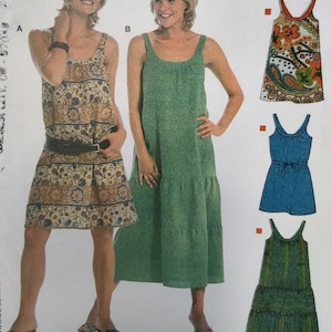 May include: Two women modeling dresses. One woman wears a patterned dress with a black belt. The other woman wears a solid green dress. The image also shows three additional dress designs: a paisley print, a blue dress with a tie, and a green tiered dress.