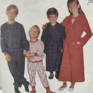 May include: Four children modeling various outfits. One child wears a blue plaid pajama set, another a red and white striped pajama set, a third a blue plaid robe, and the last a long red robe with pockets.
