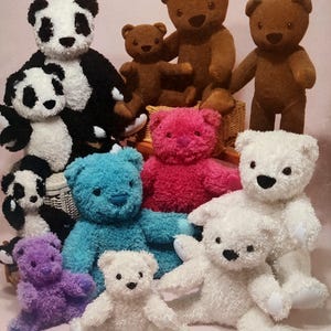 May include: A collection of plush teddy bears and pandas in various sizes and colors, including white, brown, black and white, bright pink, teal, and purple. Each stuffed animal features a textured, fuzzy exterior, dark eyes, and a stitched nose.