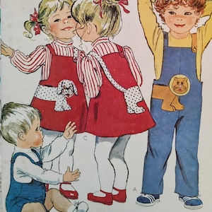 May include: A sewing pattern illustration featuring children's clothing designs. It shows a red jumper with a white dog applique, a blue overall with a lion applique, and a blue overall short set. The text "Tops not included" is printed at the bottom.