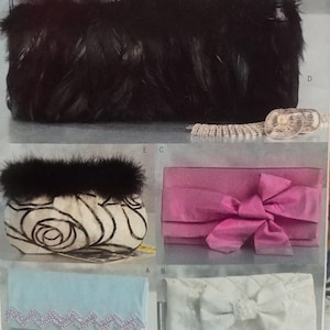 May include: A collection of five rectangular clutch bags. One is black with feathers, one is white with a black rose pattern and fur trim, one is pink with a large bow, one is light blue with sequin trim, and one is white with a bow.