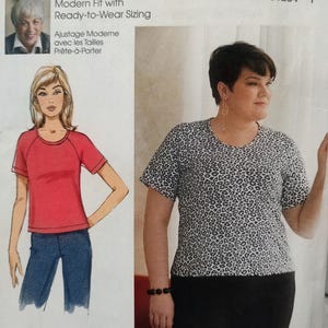 May include: A Butterick B6690 sewing pattern envelope featuring a short-sleeve t-shirt design. The package displays a technical illustration of a red t-shirt and a photograph of a person wearing a black and white leopard print t-shirt with black pants.
