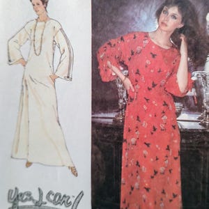 May include: A sewing pattern envelope featuring a long-sleeved floor-length dress with a round neckline and flared sleeves. The illustration shows a plain white version, while the photograph displays a red dress with a dark bird and floral print.