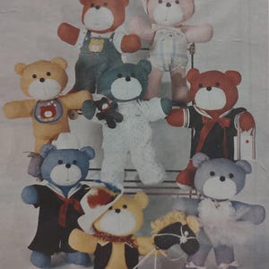 May include: A collection of handmade teddy bears in various outfits. The bears are in shades of brown, yellow, blue, and pink, with details like sailor suits, overalls, and a cowboy hat. Each bear has a white muzzle and black eyes.