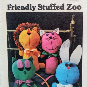 May include: A Butterick sewing pattern envelope titled Friendly Stuffed Zoo featuring illustrations of four plush animals: an orange lion with a brown mane, a pink cat, a green cat with purple ears, and a blue rabbit with white ears.