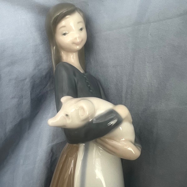 Figurine de Lladró, 1011 Jeune fille tenant un porcelet dans ses bras. État neuf d'occasion. Porcelaine/finition brillante 1977.