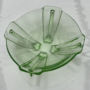 May include: A green glass bowl with a unique design. The bowl has five points and a fluted edge. It is perfect for serving snacks or desserts.