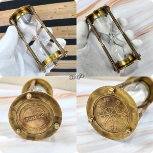 May include: An antique-style hourglass with a brass frame and clear glass bulbs. The base features a compass design and the text "YOUR TIME CRAPLE 1920 YOUR STORY". A classic decorative item.