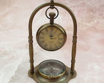 May include: A brass antique-style pocket watch with a compass on a stand. The watch face reads "Victoria London 1915".