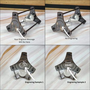 May include: A black metal hourglass with a clear glass bulb. The hourglass has a unique design with a decorative frame. The image shows different engraving options, including the text "Your Engrave Message Will Be Here", "No Engraving", "AS", and "From 1940".