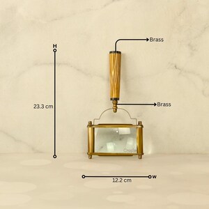 May include: A brass magnifying glass with a wooden handle, measuring 9.17 inches in height and 4.8 inches in width. The handle has a textured design. The magnifying glass has a rectangular shape and is labeled "Craple".