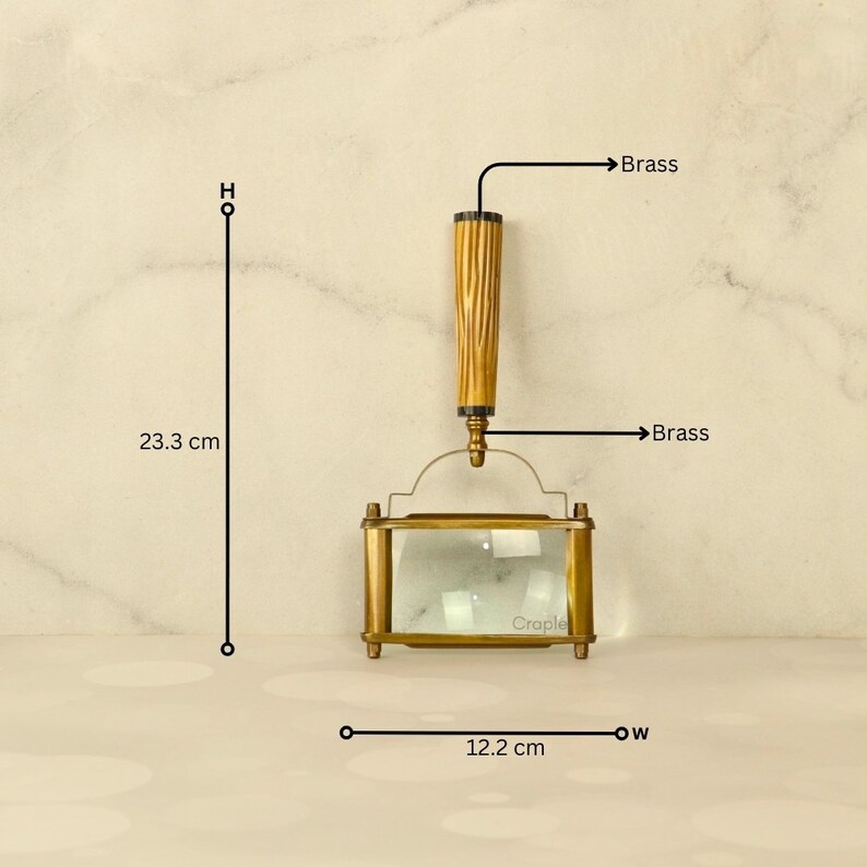 May include: A brass magnifying glass with a wooden handle, measuring 9.17 inches in height and 4.8 inches in width. The handle has a textured design. The magnifying glass has a rectangular shape and is labeled "Craple".