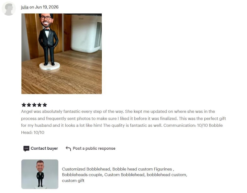 May include: A custom bobblehead figurine featuring a person with brown hair and glasses, wearing a black tuxedo with a white shirt and a black bow tie. The figure stands on a round white base and is depicted with hands resting on the hips.