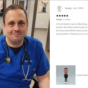 May include: A 5-inch tall custom bobblehead figurine depicting a person wearing a black scrub top with a stethoscope draped around the neck. The figure features brown hair and facial scruff, standing on a small circular white base.