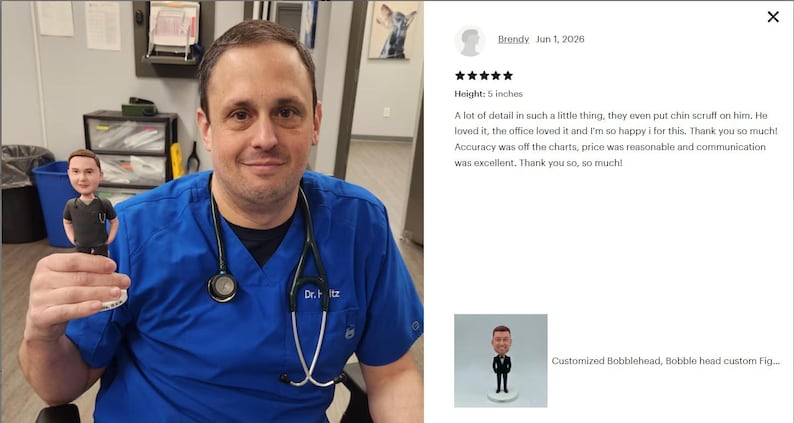 May include: A 5-inch tall custom bobblehead figurine depicting a person wearing a black scrub top with a stethoscope draped around the neck. The figure features brown hair and facial scruff, standing on a small circular white base.
